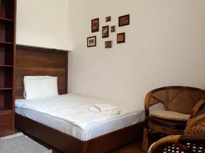 a bedroom with a bed and a chair and pictures on the wall at Guest Rooms Maria Luiza in Varna City