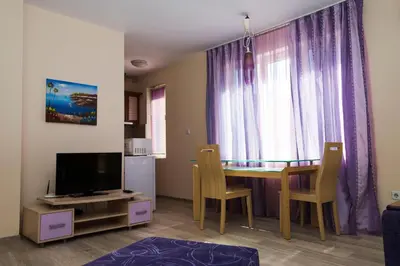 a living room with a dining room table and a tv at Aquaria Holiday Apartments in Sunny Beach