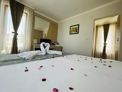 two white swans sitting on a bed with roses on it at Melia Mar in Sozopol