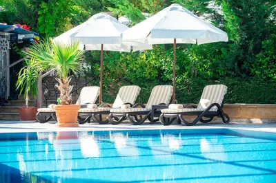 three chairs and umbrellas next to a swimming pool at Siena Palace in Primorsko