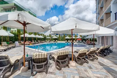 a resort pool with chairs and umbrellas at Siena Palace in Primorsko