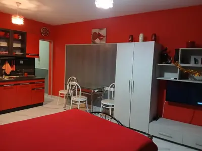 a kitchen with red walls and a table and chairs at Studio Nera in Pomorie