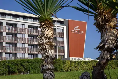 a hotel with palm trees in front of a building at Aparthotel Paradiso in Nesebar