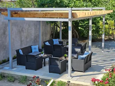 a pergola with chairs and tables on a patio at Family House Manolov in Obzor