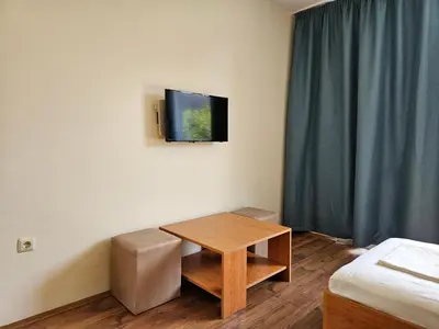 a room with a table and a tv on the wall at Family House Manolov in Obzor
