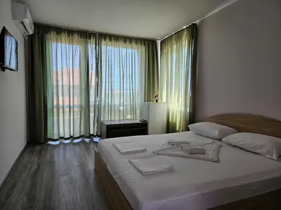 a bedroom with a large bed and a large window at Family House Manolov in Obzor