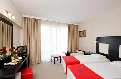 a hotel room with two beds and a desk at Calypso Hotel - All Inclusive in Sunny Beach