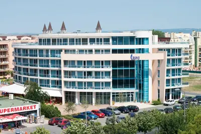 a large white building with cars parked in a parking lot at Calypso Hotel - All Inclusive in Sunny Beach