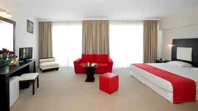 a hotel room with a red bed and a red chair at Calypso Hotel - All Inclusive in Sunny Beach
