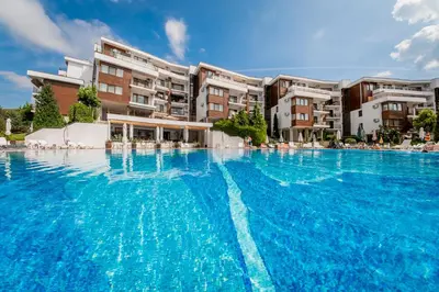 a large swimming pool with blue water in front of buildings at Messambria Fort Noks Beach Apartments in Elenite