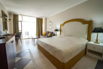 a bedroom with a large bed and a living room at Imperial Palace Hotel in Sunny Beach