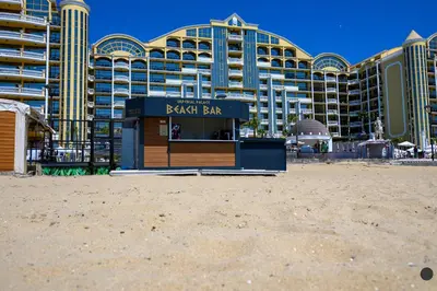 a beach bar in front of a large building at Imperial Palace Hotel in Sunny Beach