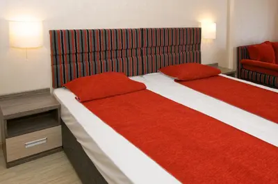 two beds in a hotel room with red covers at Hotel Kotva - All Inclusive in Sunny Beach