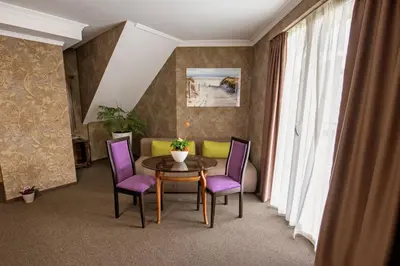 a living room with a table and purple chairs at Hotel Perfect in Varna City