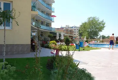 a man standing next to a building with a swimming pool at Julia Family Apartments in Sunny Beach