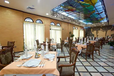 a dining room with tables and chairs and a stained glass ceiling at Art Hotel Babylon in Sunny Beach