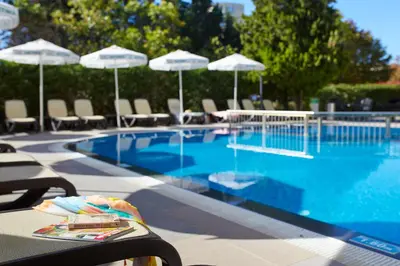 a swimming pool with chairs and umbrellas next to it at Hotel Aktinia - All Inclusive in Sunny Beach