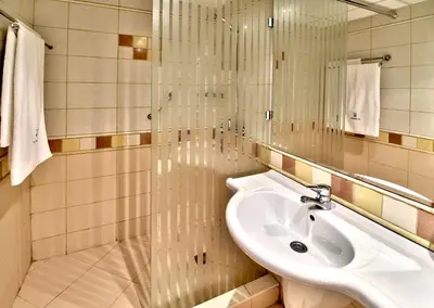 a white bathroom with a sink and a shower at Les Magnolias Hotel in Primorsko