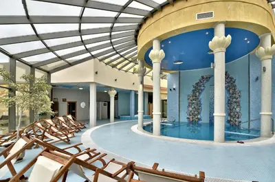 a large swimming pool with chairs in a building at Les Magnolias Hotel in Primorsko