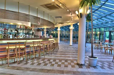 a restaurant with a bar with chairs and tables at Les Magnolias Hotel in Primorsko