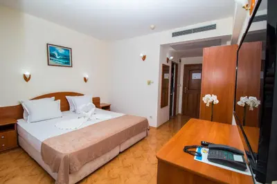 a bedroom with a bed and a television and a desk at Hotel Sunny in Sozopol