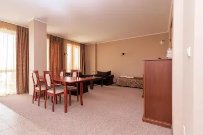 a living room with a table and chairs and a bedroom at Festa Pomorie Resort in Pomorie