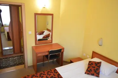 a bedroom with a desk and a bed and a mirror at Stankoff Hotel in Nesebar