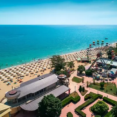 a beach with a lot of umbrellas and a roller coaster at Hotel Fenix - All Inclusive in Sunny Beach