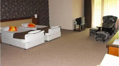 a hotel room with two beds and a chair at Hotel Park in Karnobat
