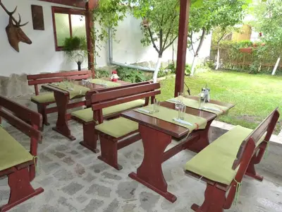 a patio with wooden tables and benches and a yard at Hotel Beroe in Sveti Vlas
