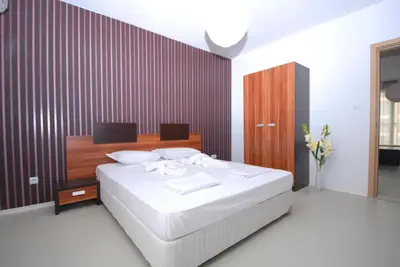 a bedroom with a white bed and a wooden wall at Boutique Suites Rainbow 4 in Sunny Beach