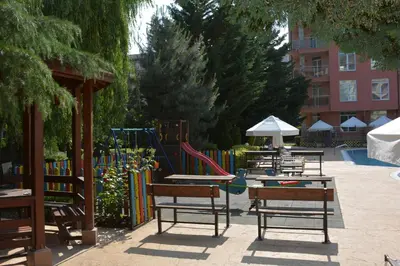 a group of tables and chairs with a playground at Rainbow 2 Holiday Complex in Sunny Beach