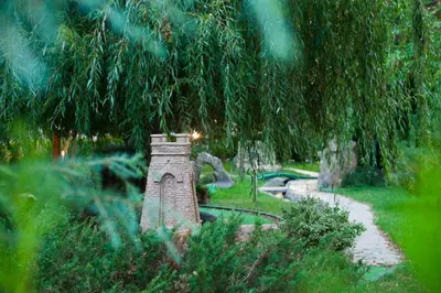 a garden with a stone tower in the middle of a park at Rainbow 2 Holiday Complex in Sunny Beach