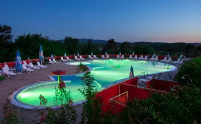 a large swimming pool with lawn chairs and umbrellas at Hotel Coop - Kiten in Kiten