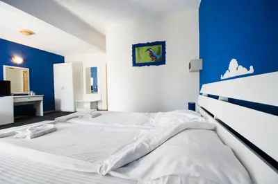 a bedroom with a large white bed with a blue wall at Family Hotel Four Seasons Tsarevo in Tsarevo