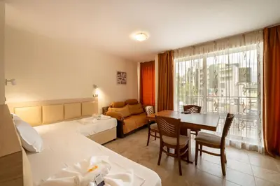 a hotel room with a bed and a dining room at Perla Apartments in Nesebar