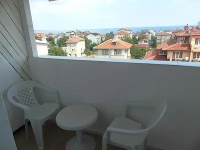 a balcony with two chairs and a table and a window at Apartments Ivelin in Lozenets