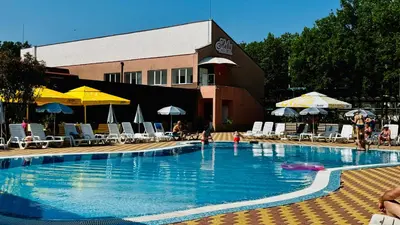 a large swimming pool with chairs and umbrellas at Hotel Neva in Kiten
