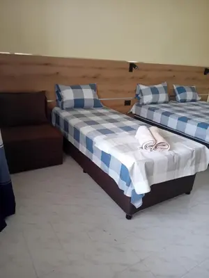 two beds sitting next to a couch in a room at Guesthouse Oasis in Kiten