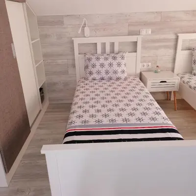 a small bedroom with a white bed and a table at Apartments Dona in Chernomorets