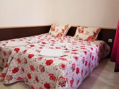 a bed with a red and white blanket and pillows at Family Aparthotel Vintegra in Burgas City