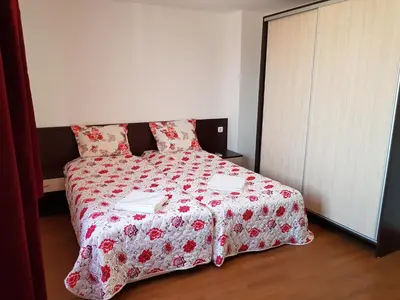 a bedroom with a bed with a red and white comforter at Family Aparthotel Vintegra in Burgas City