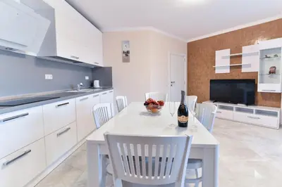 a kitchen with white cabinets and a white table and chairs at VILLA FLORENCE Boutique Apart Hotel in Sveti Vlas