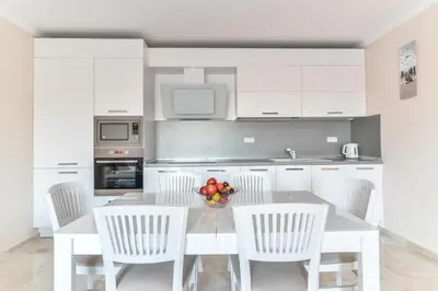 a kitchen with a table with chairs and a bowl of fruit at VILLA FLORENCE Boutique Apart Hotel in Sveti Vlas