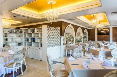 a dining room with tables and chairs and chandeliers at VILLA FLORENCE Boutique Apart Hotel in Sveti Vlas