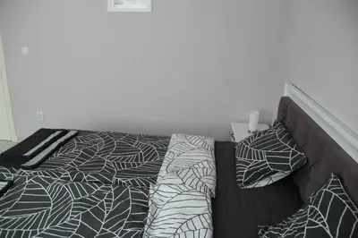 a bed with black and white sheets and pillows at Karchevi Apartment in Sveti Vlas