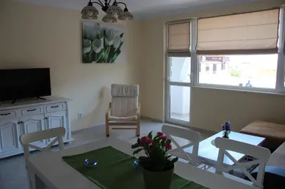 a living room with a table and chairs and a television at Karchevi Apartment in Sveti Vlas