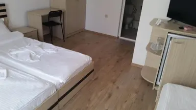 a bedroom with a white bed and a wooden floor at The Sea Lions Guest House in Tsarevo