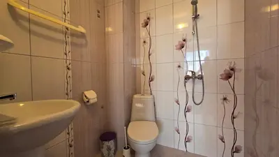 a bathroom with a toilet and a sink with flowers on the wall at Estreya in Tsarevo