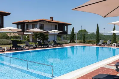 a large swimming pool with chairs and umbrellas at Villas in Complex Trakiyskiy Bryag in Lozenets